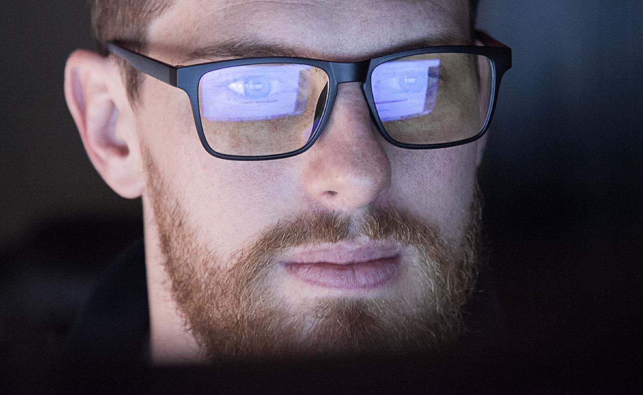 A young man wearing blue light blocking glasses