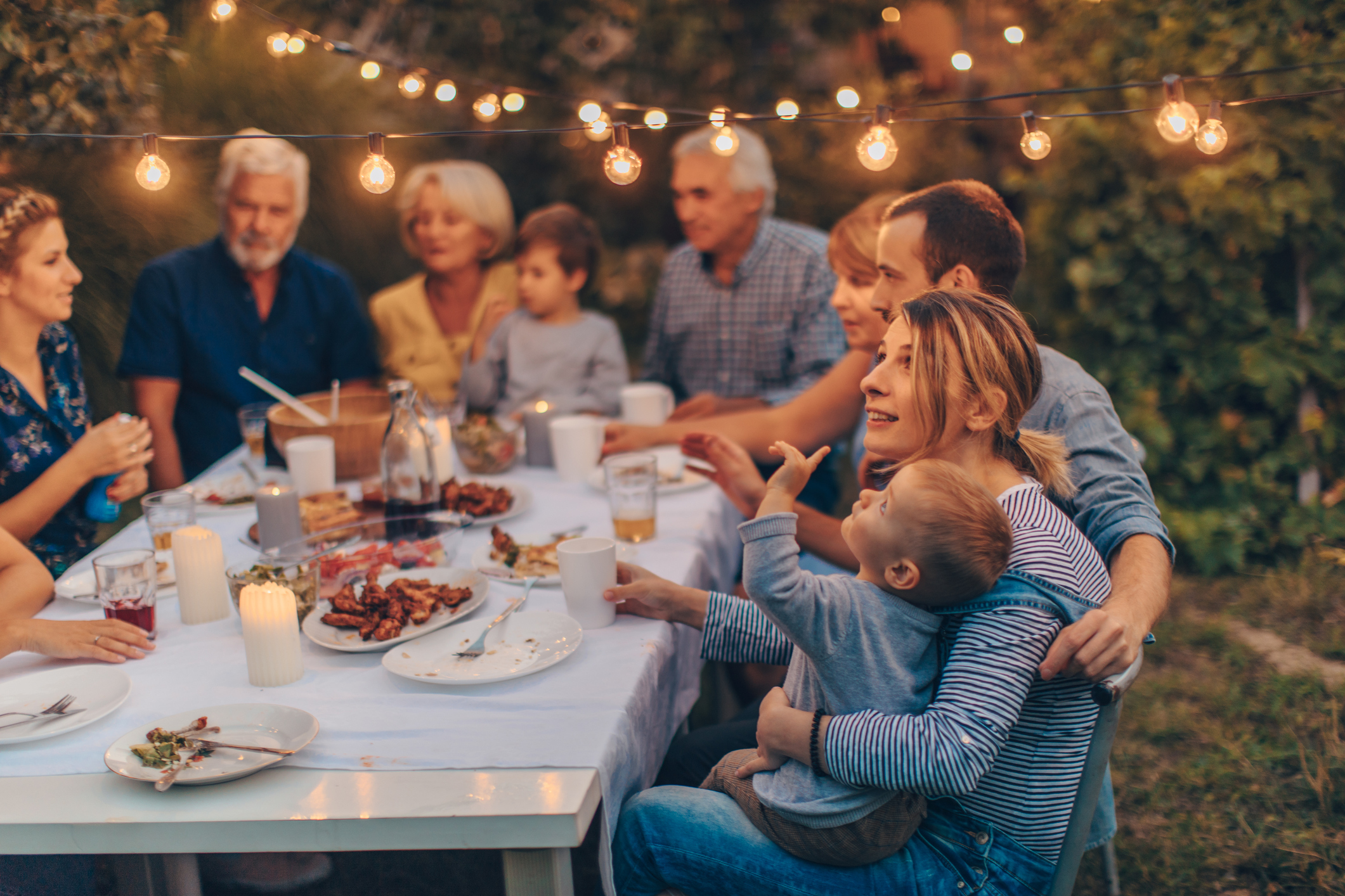 Photo of a big family during dinner, celebrating holiday together in the backyard